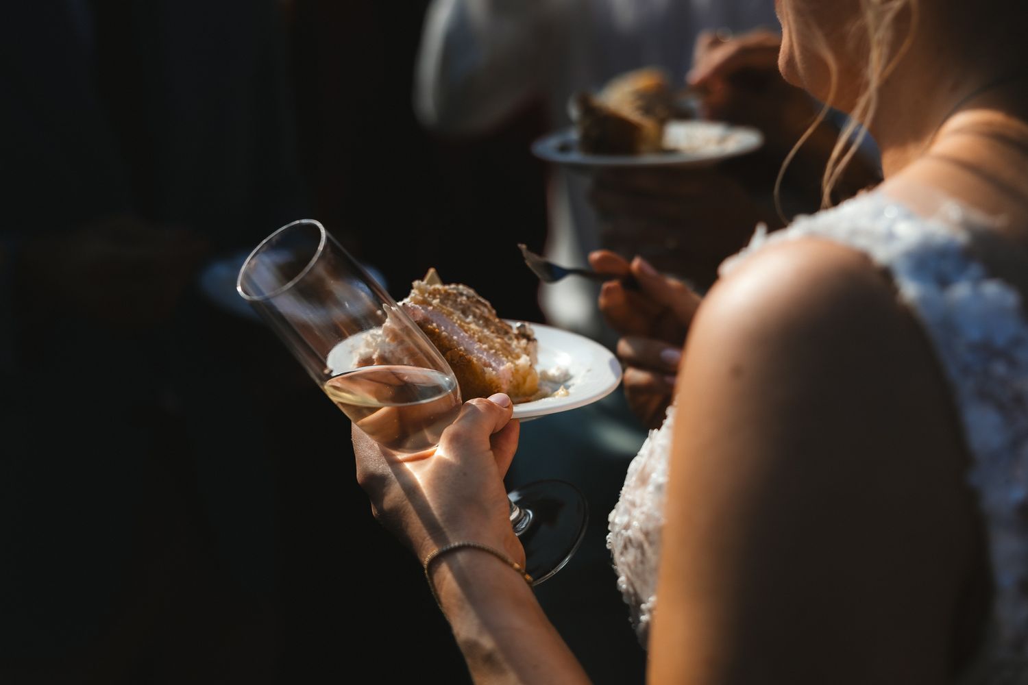 Someone wearing bracelets holding a glass of whiskey with steam or smoke rising in a dark moody setting.
