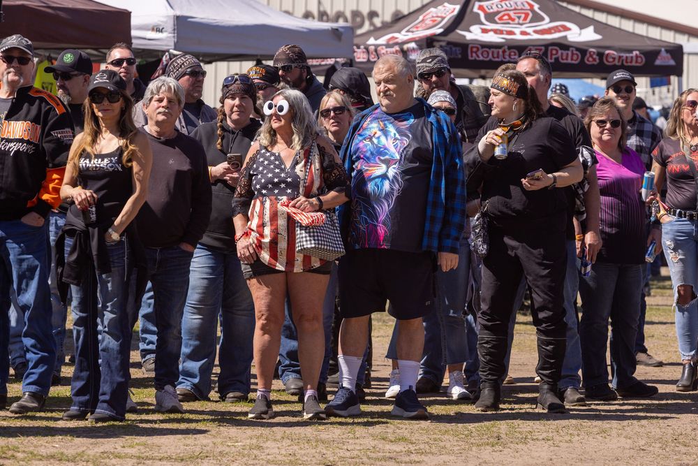 A crowd of spectators watching an outdoor motorcycle event on a dirt field.