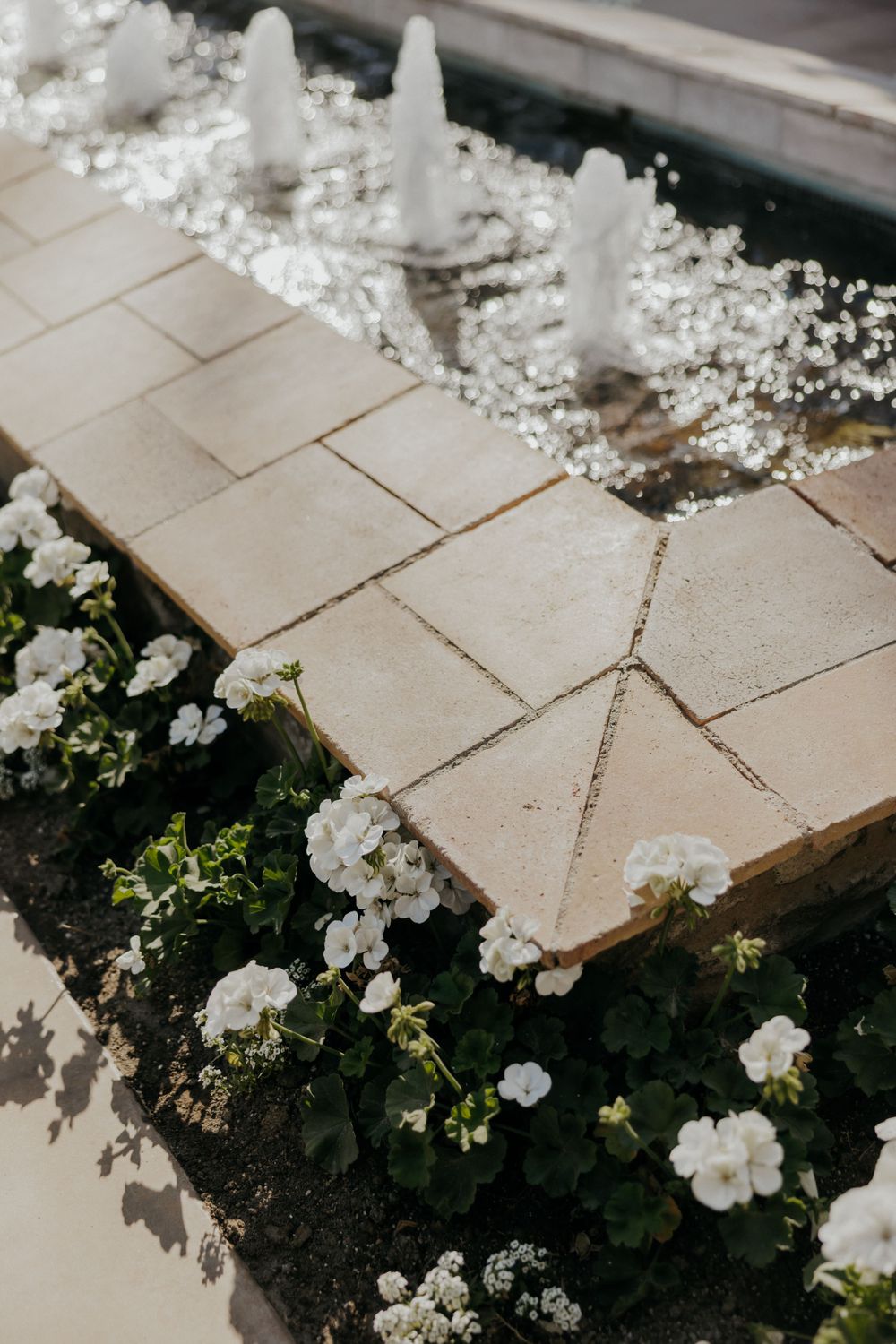 White flowers and decorative elements line a stone pathway in a manicured garden.