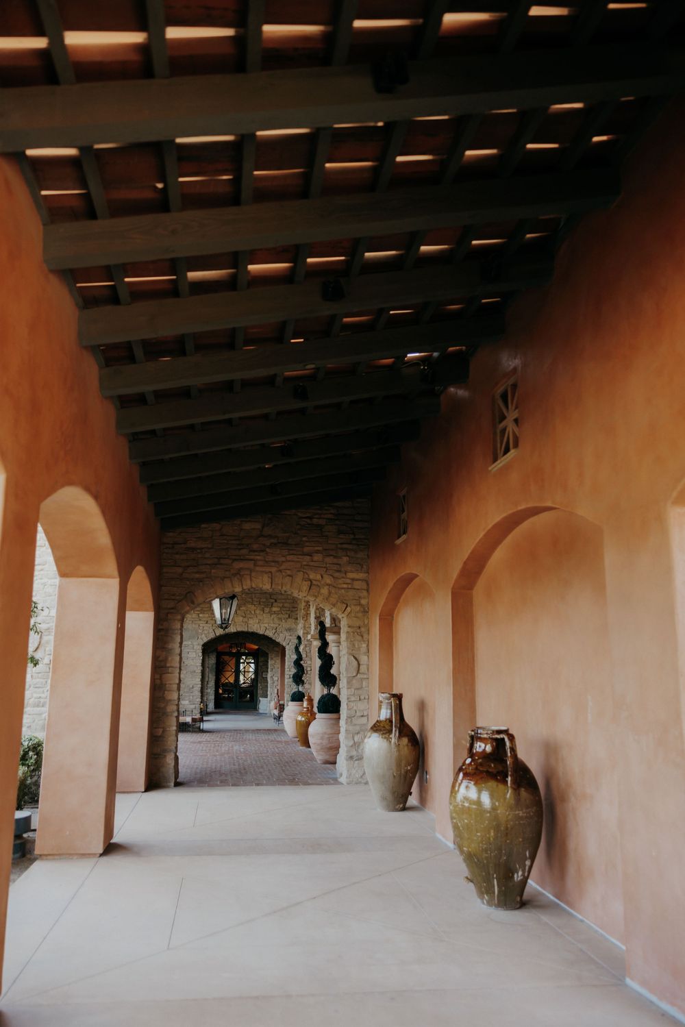 Mediterranean style corridor with terracotta walls, wooden beams, and decorative pottery.
