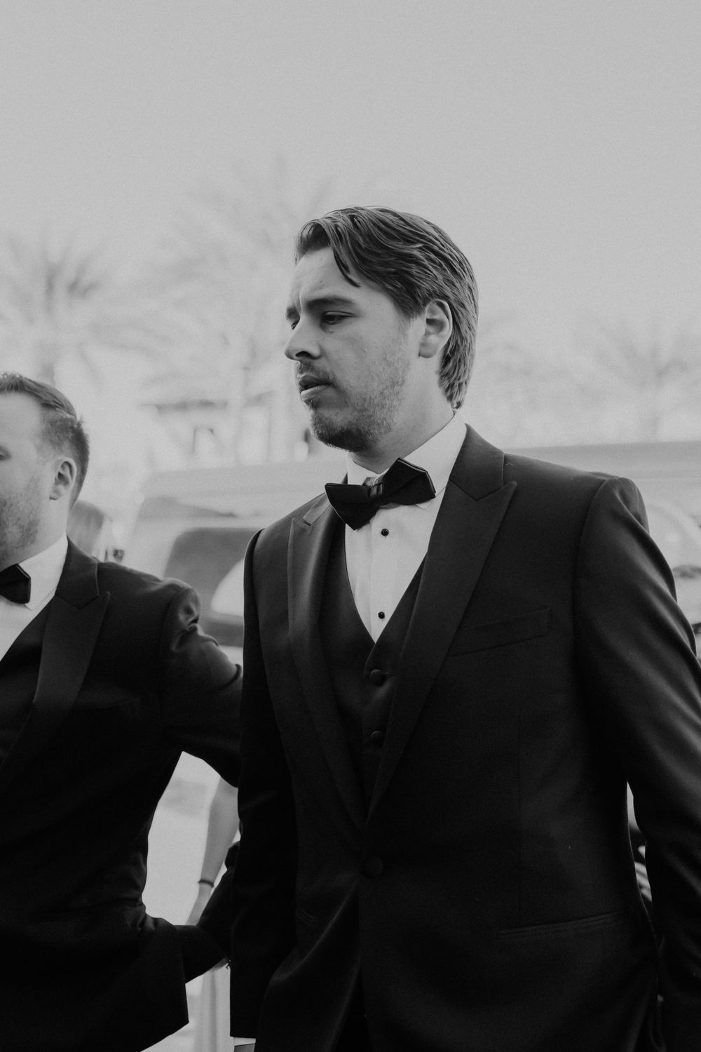 Formal event attendee in classic black tuxedo and bowtie outdoors.