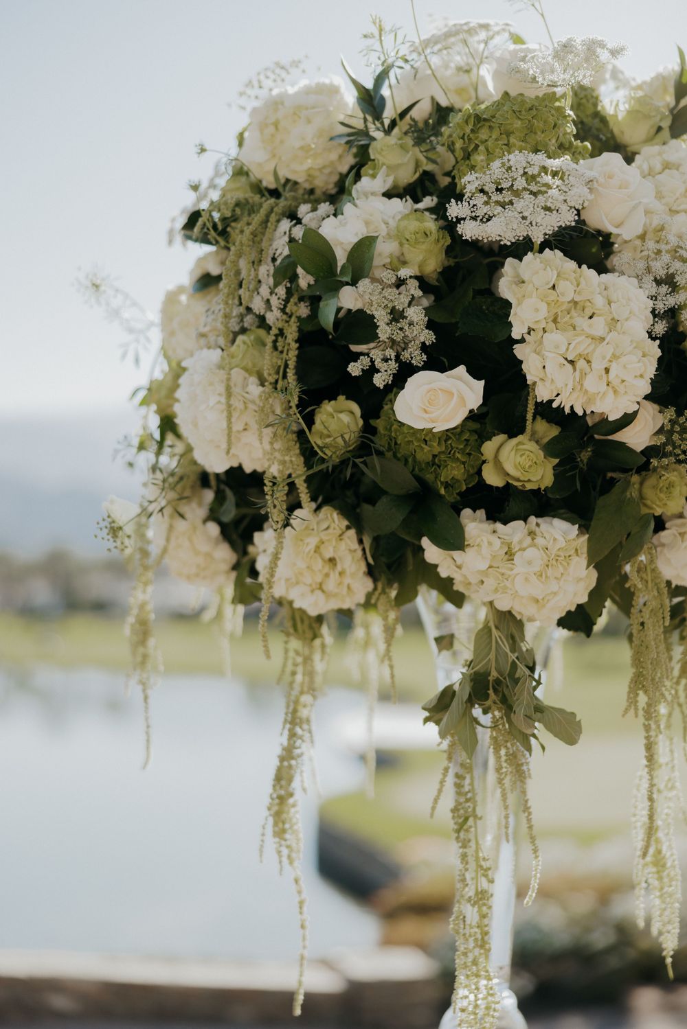 Elegant white floral arrangement with cascading greenery and roses.