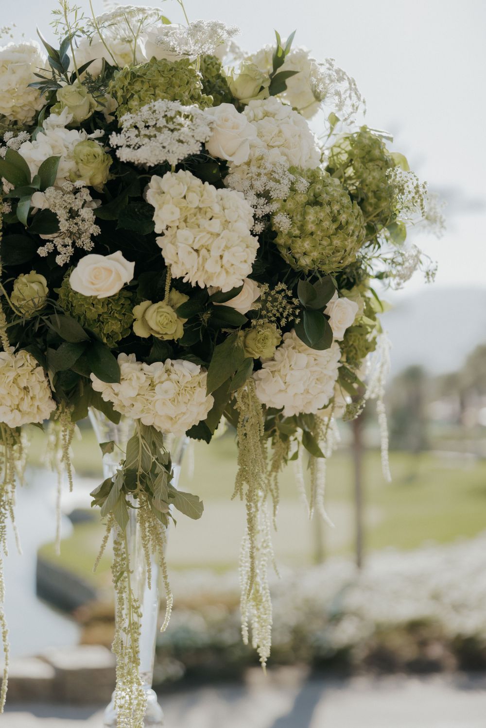 Close-up of luxurious white wedding flower arrangement with trailing greenery.