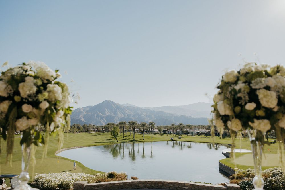 Wedding arch decorated with white floral arrangements overlooking a scenic mountain lake.