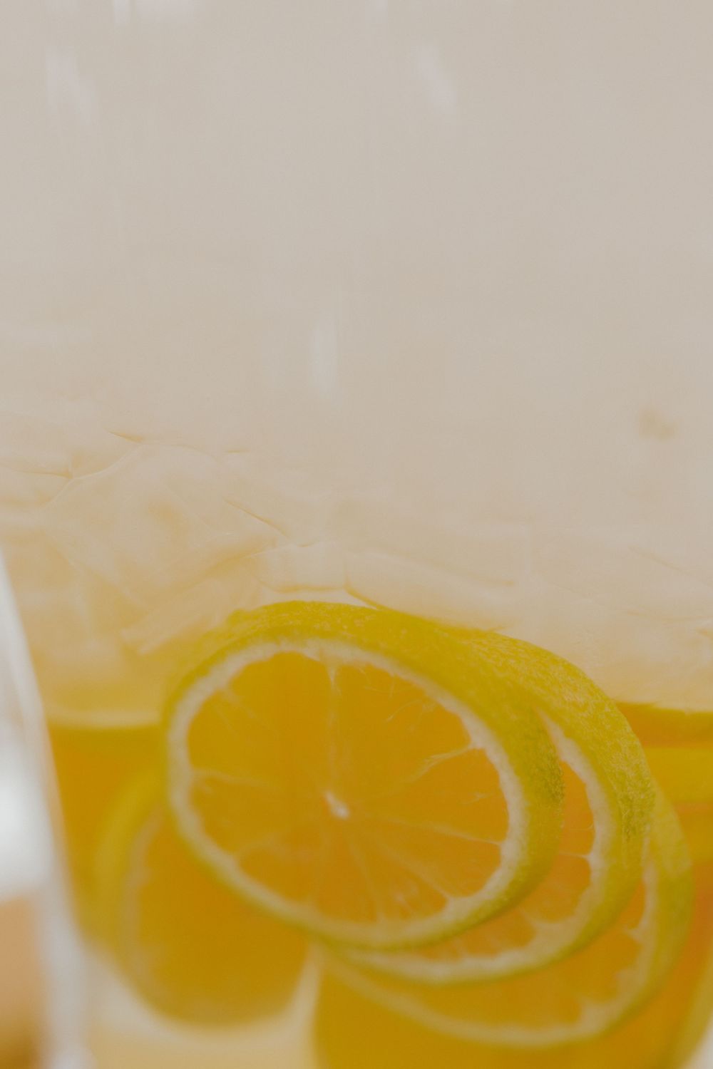 Citrus lemon slices floating in yellow refreshing beverage.