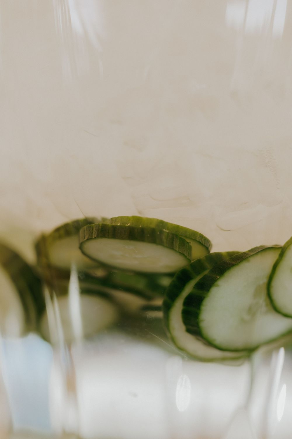 Close-up of cucumber slices floating in a clear beverage glass.