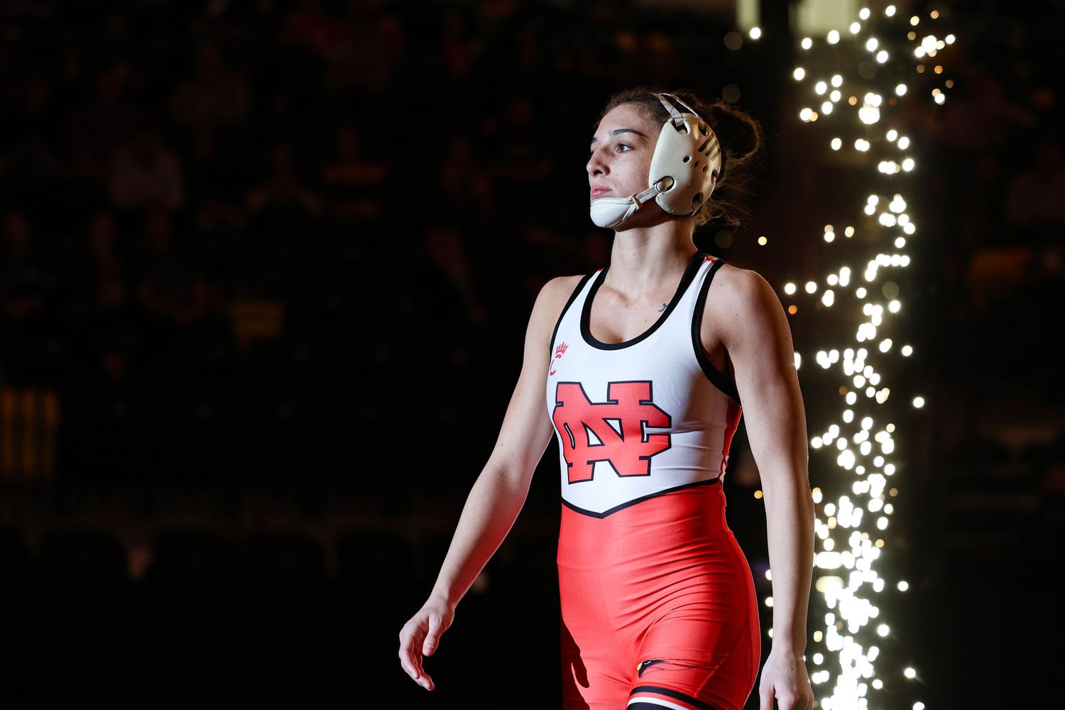 Athletes stand with referee after a wrestling match with one signaling victory.