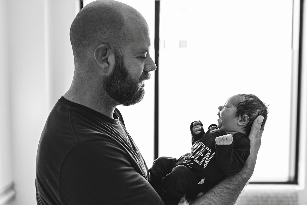 A-dad-holding-his-newborn-son-up-for-pictures-at-his-fresh-48-session-in-his-hospital-room-at-St.Francis-hospital