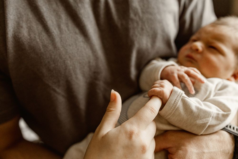 Newborn-baby-boy-holding-onto-his-moms-finger-at-their-newbron-session-in-Tulsa