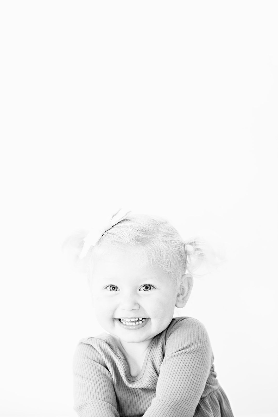 Artistic high key black and white photograph of toddler girl on sold white background at her family home near Lancaster in Lancaster County.