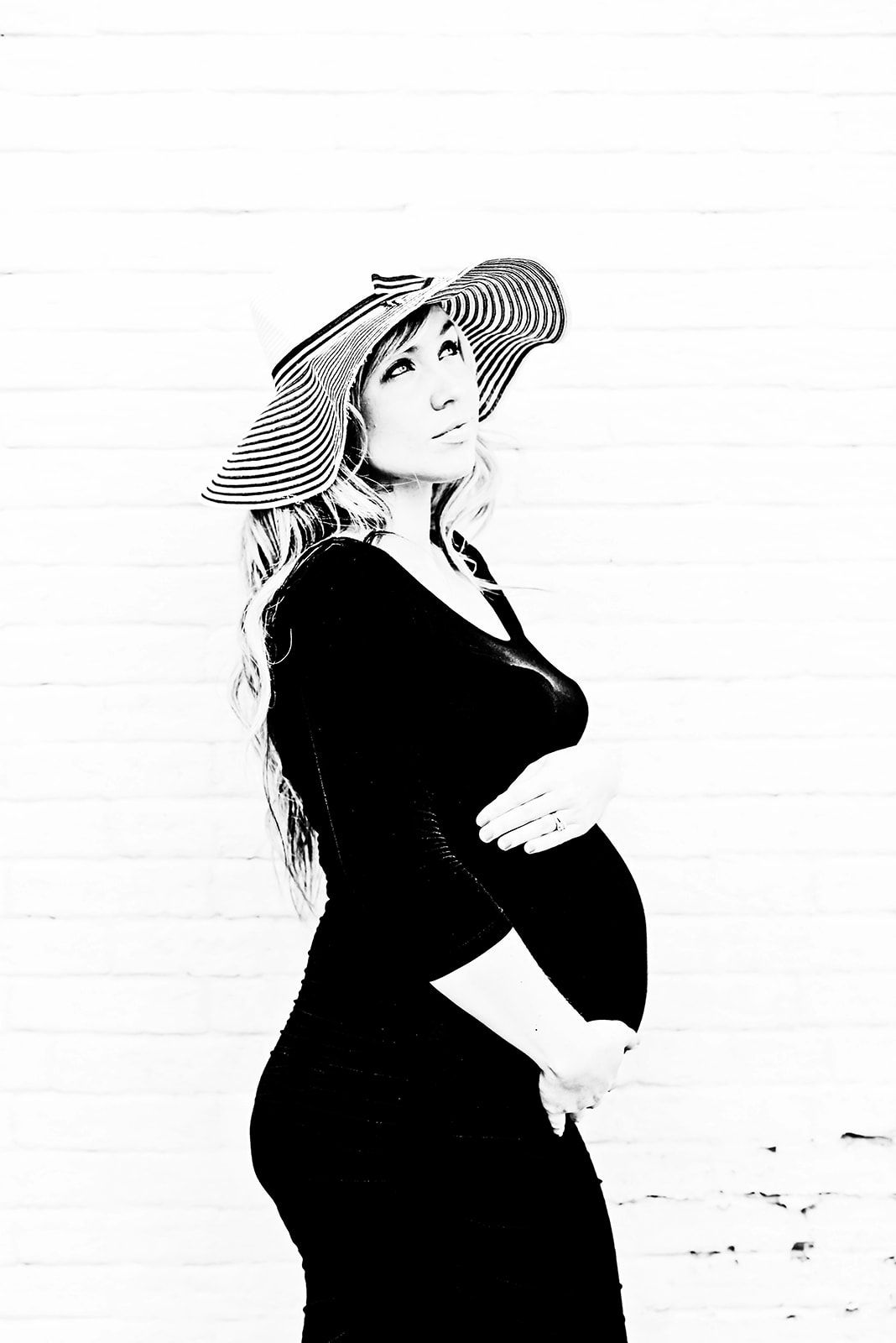 Black and white photo of pregnant woman with her hands placed on her belly in the city near Harrisburg PA in Dauphin County.