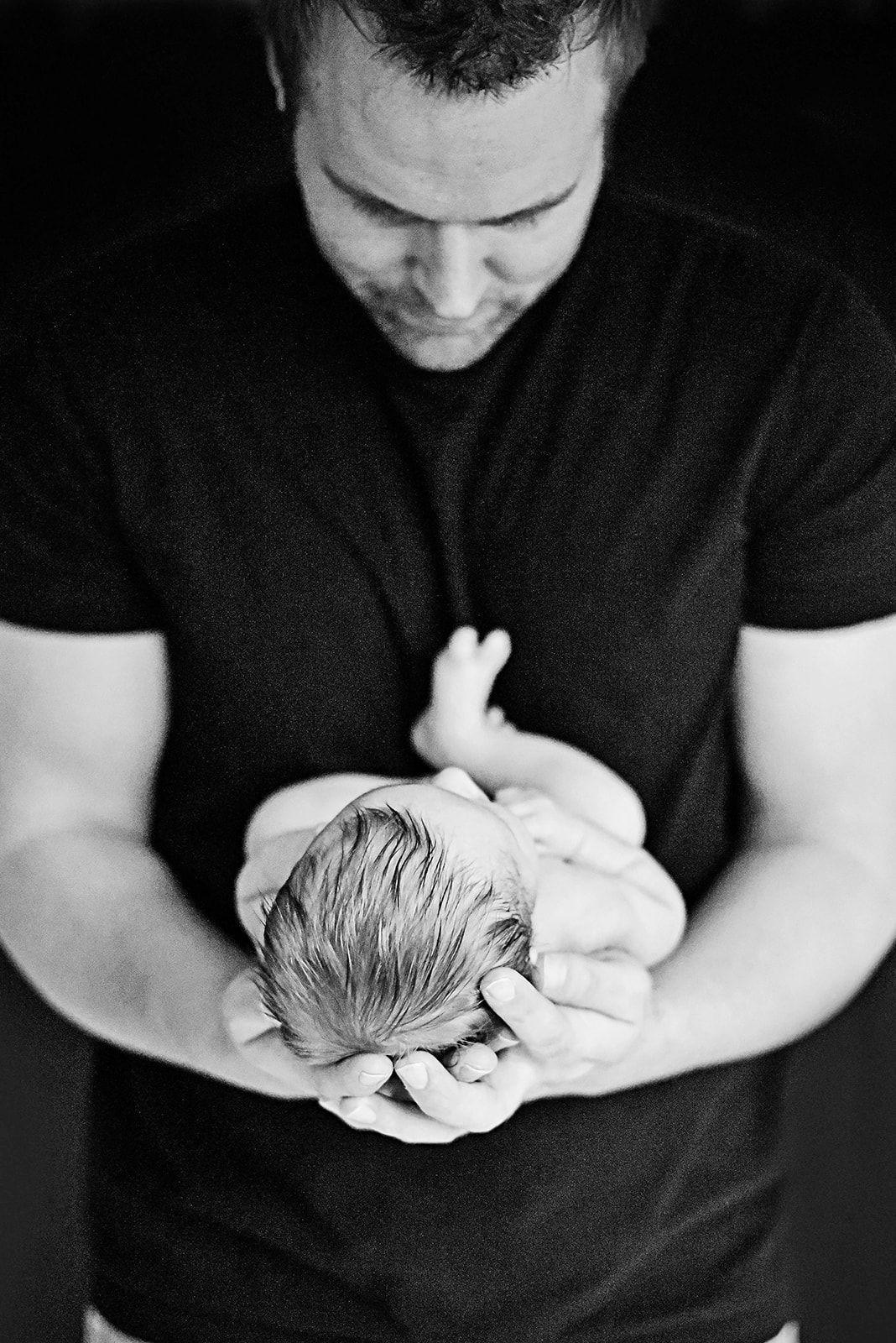 Photograph of newborn in dad's hands as dad admires baby near Boiling Springs in Cumberland County PA