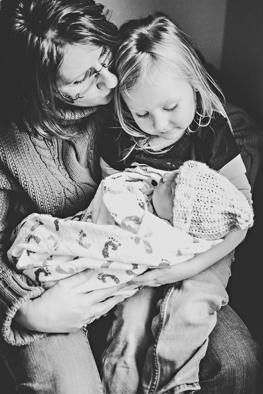 A black and white photo of child and grandparent meeting newborn baby at the hospital, 48 hours after birth near Hershey PA.
