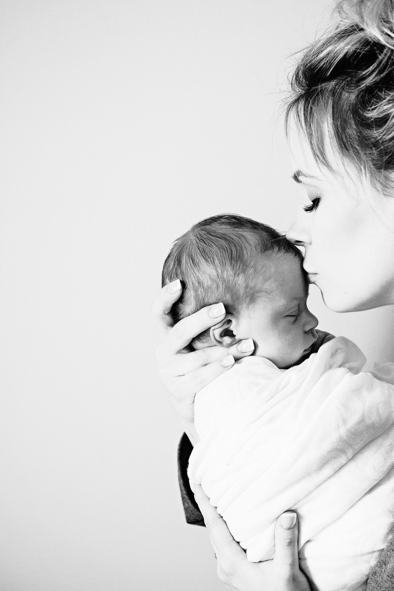 A high key black and white artistic photograph showing tender moment between mother and newborn in their home near Camp Hill PA.