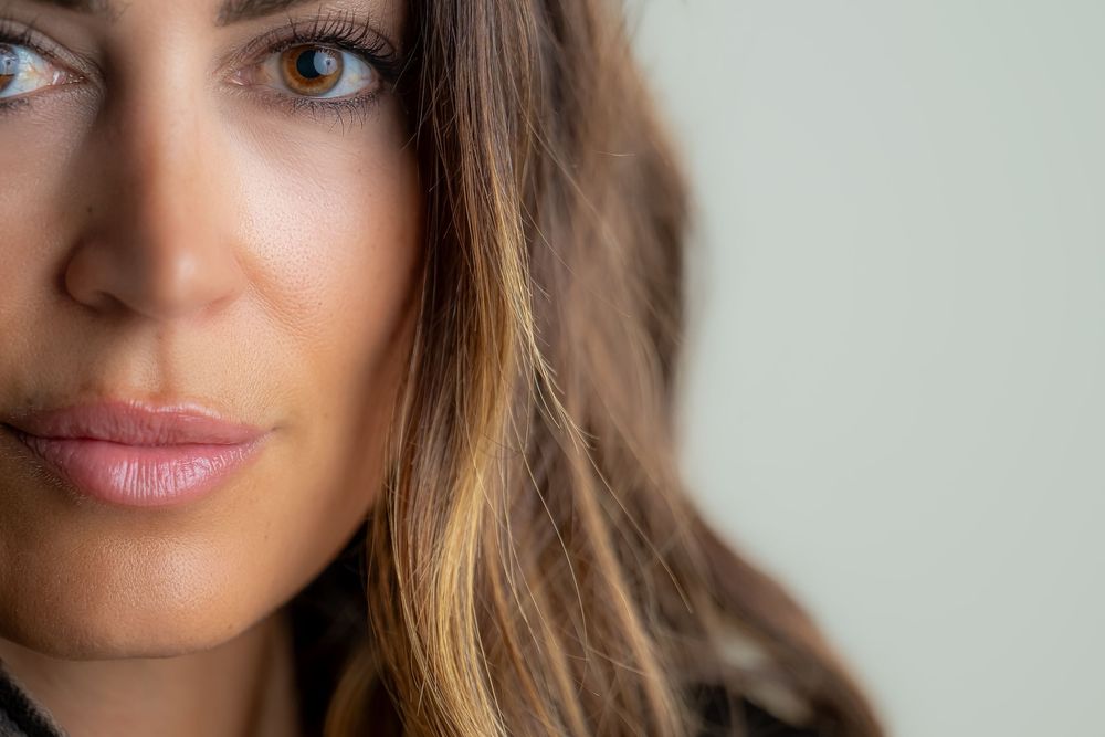 Close up beauty portrait with soft lighting showing lush lips and long brunette hair with highlights.