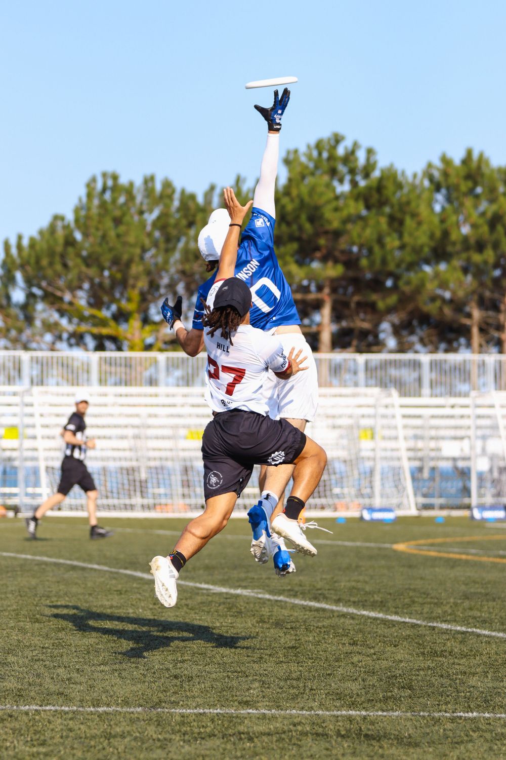Ultimate frisbee players making diving catches on grass field during competitive game.