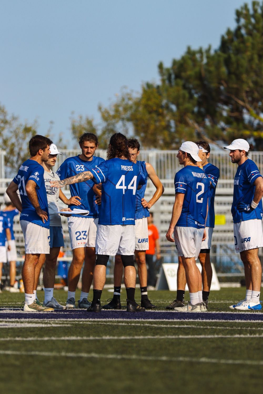 Ultimate frisbee team gathered on sideline during game break at outdoor sports venue.