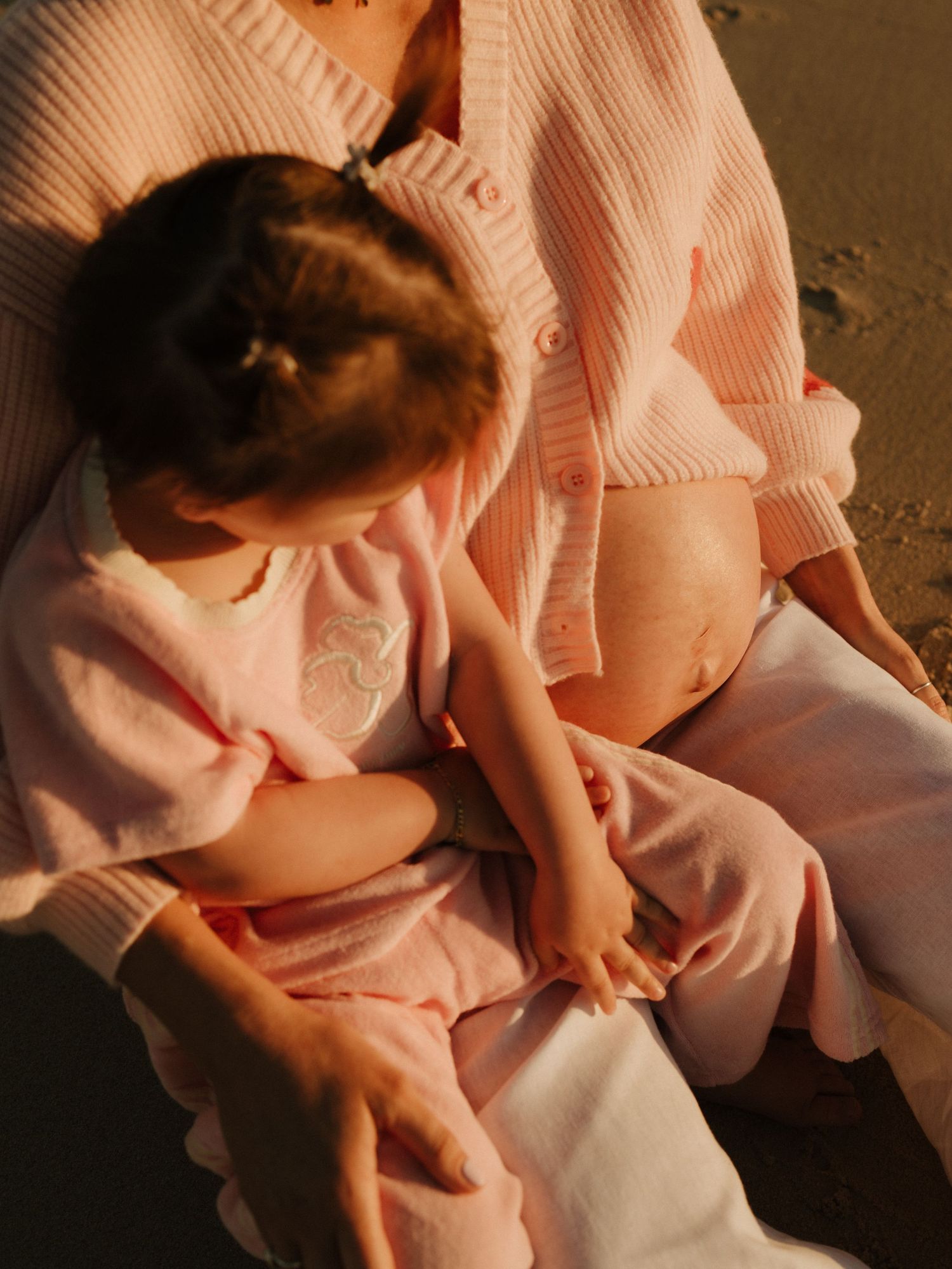 Close-up of hands in soft pink lighting gently touching and creating intimate gestures.