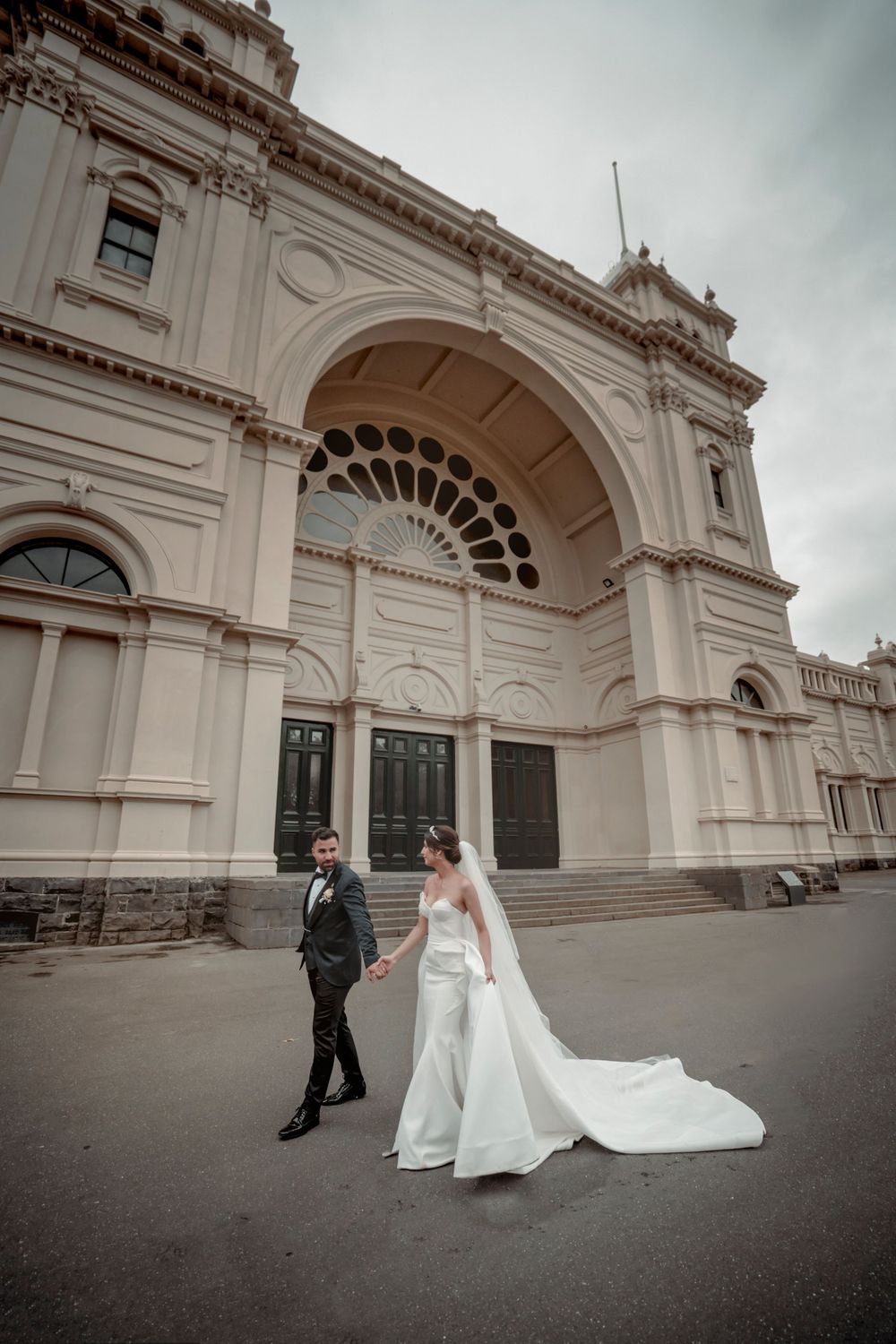 A wedding couple walks outside a grand historic building with classical architecture.