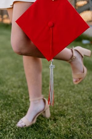 Close-up sequence showing red graduation cap tassels swaying against green grass background.