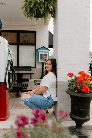 A casual outdoor scene with flowering planters, a white painted wall, and a vintage gas pump displayed as decor.