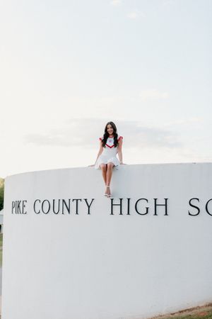 A white wall leads to a partial view of Pike County High School signage on a sunny day.