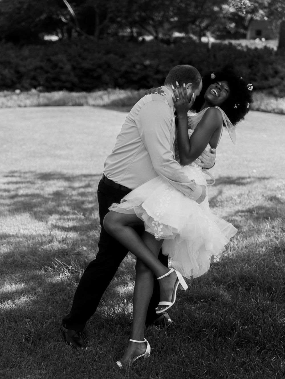 A romantic black and white photo of a couple dancing in a loving embrace outdoors.