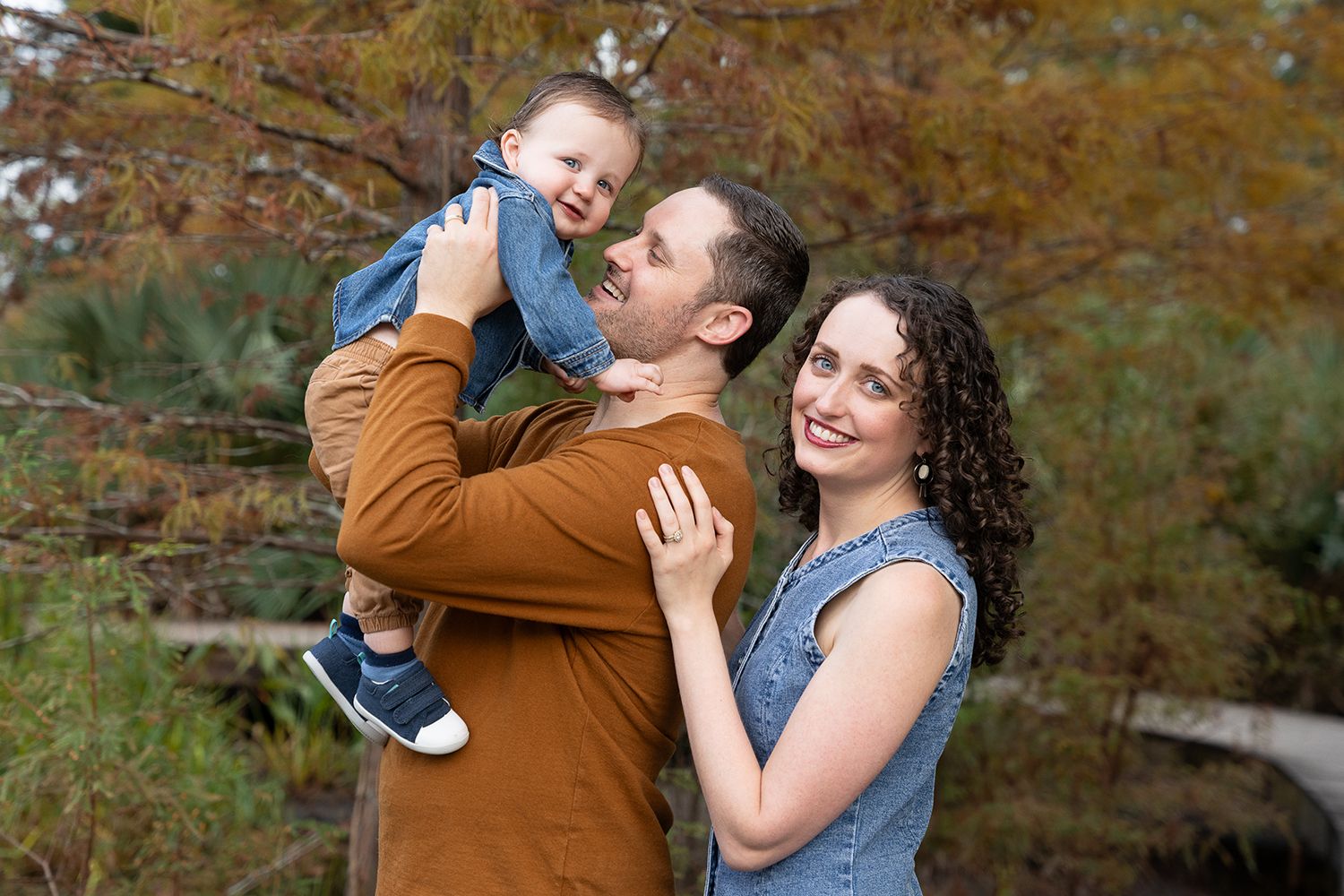 Family poses on wooden bridge during autumn with split portrait composition.