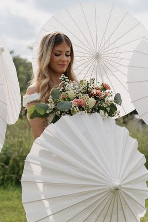 A white paper parasol adds an elegant touch to this romantic outdoor photo session with floral accents.