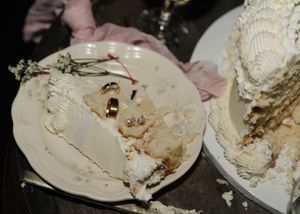 Two messy plates covered in smeared white frosting and cake remnants sit on a dark surface.