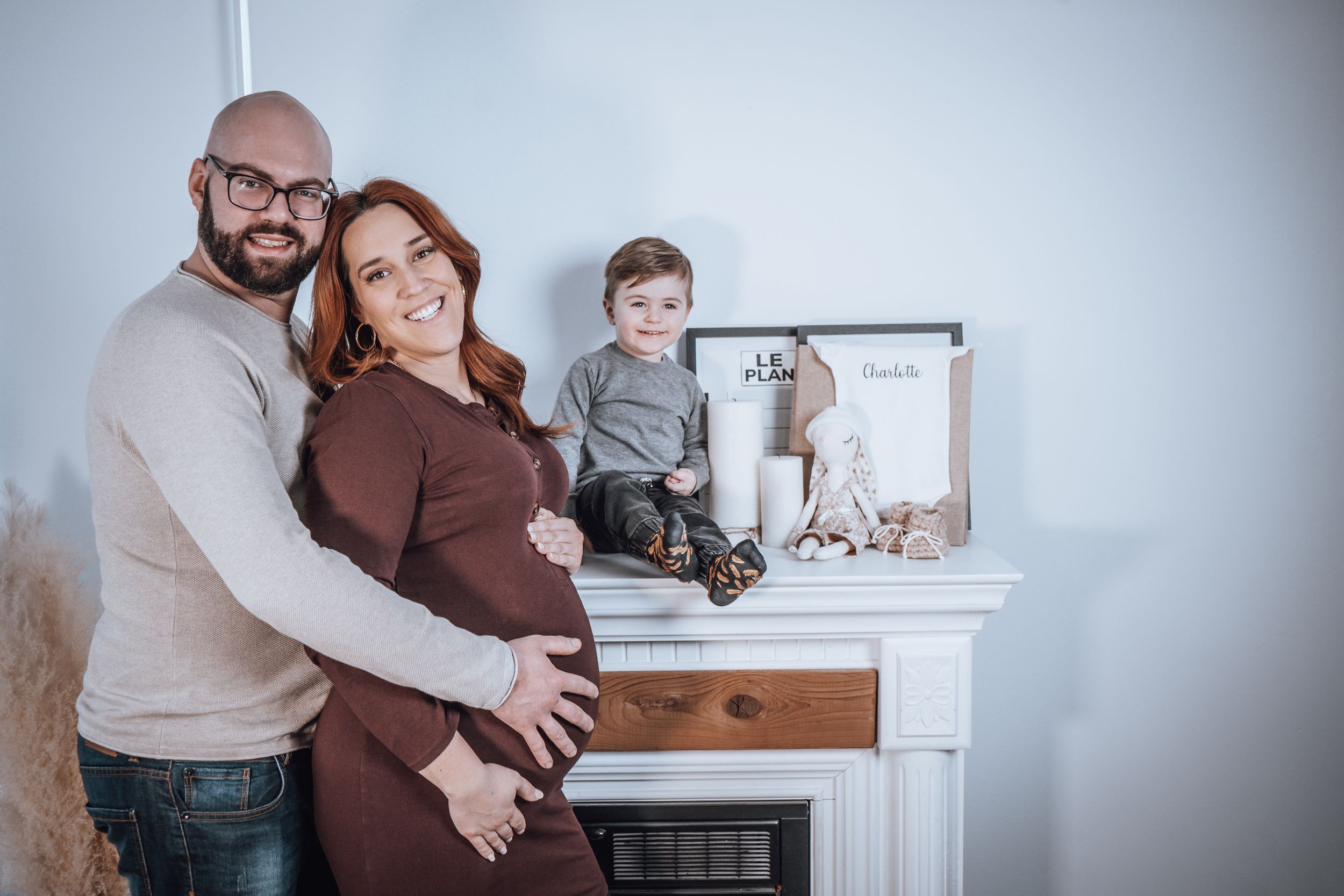 Family portrait in front of white fireplace mantel in cozy home setting.