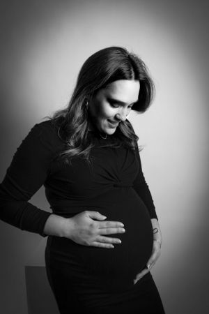 Black and white maternity portrait showing an expectant mother in dark clothing.