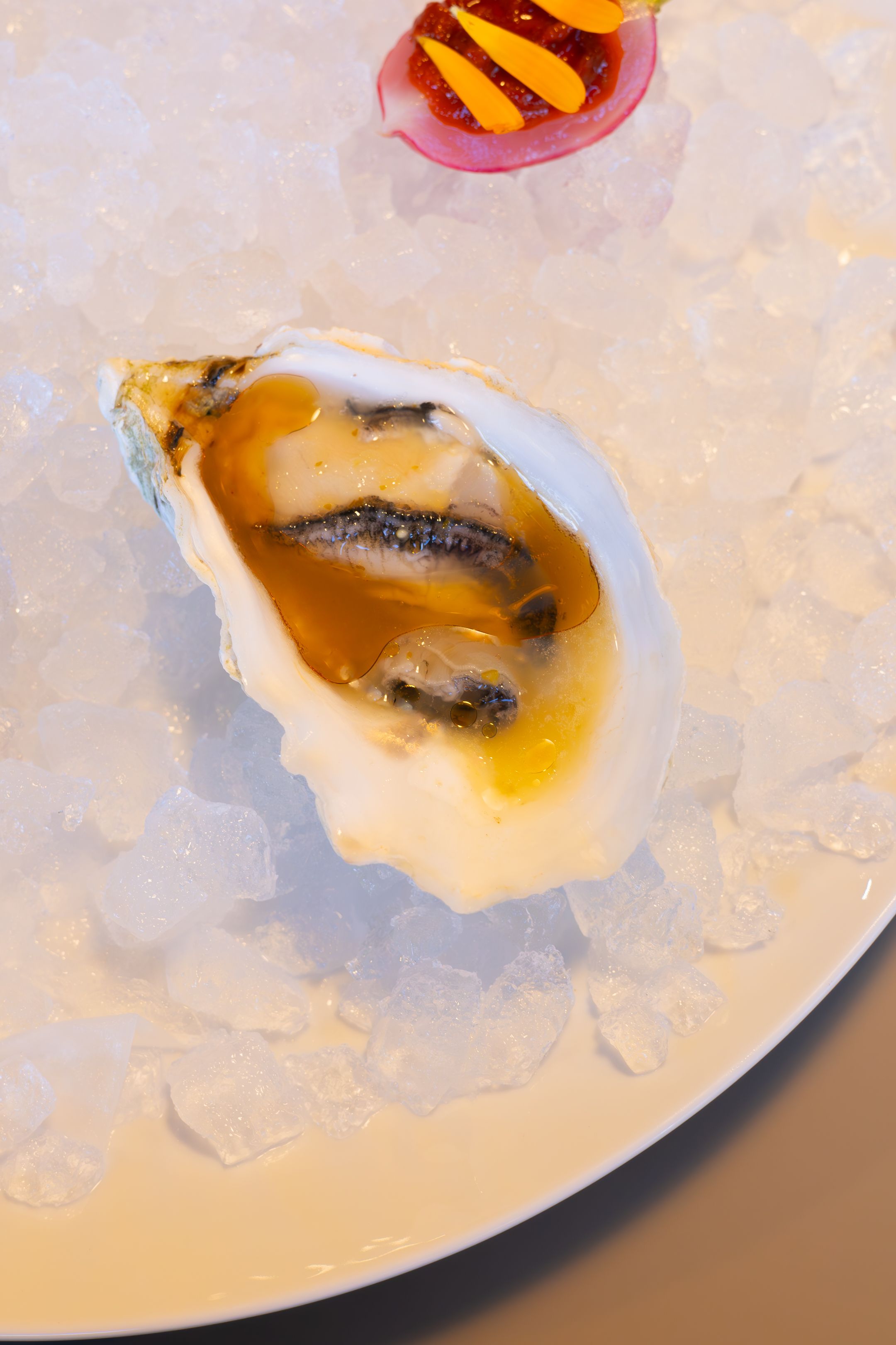Fresh oyster with sauce served on a bed of crushed ice.