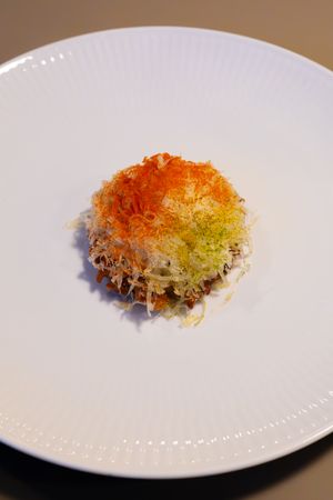 Crispy colorful dish with orange and green gradient toppings on white plate.