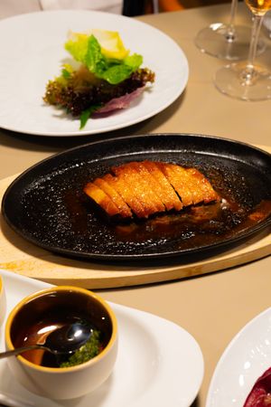 Perfectly cooked teriyaki dish on black plate served with dipping sauce and fresh salad.