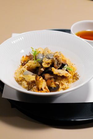Cauliflower and mushroom medley garnished with fresh herbs served in a white bowl.