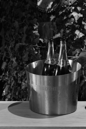 Champagne bottles chilling in stainless steel ice bucket photographed in black and white.