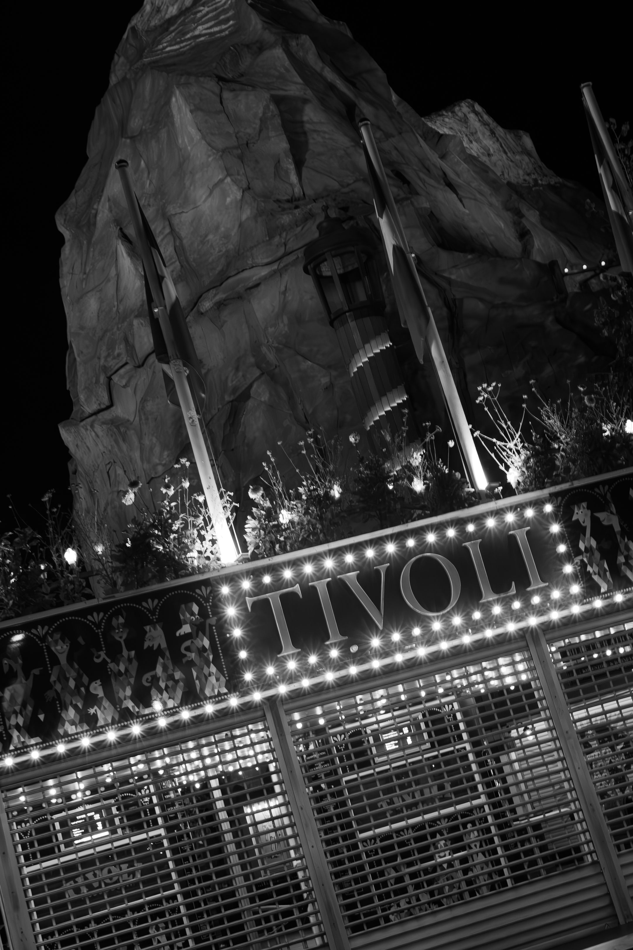 Illuminated Tivoli sign against rock formation backdrop with dramatic nighttime lighting.