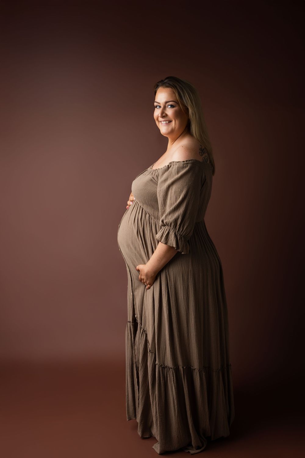 A maternity photoshoot series showing a person in a brown dress against a dark background from different angles.