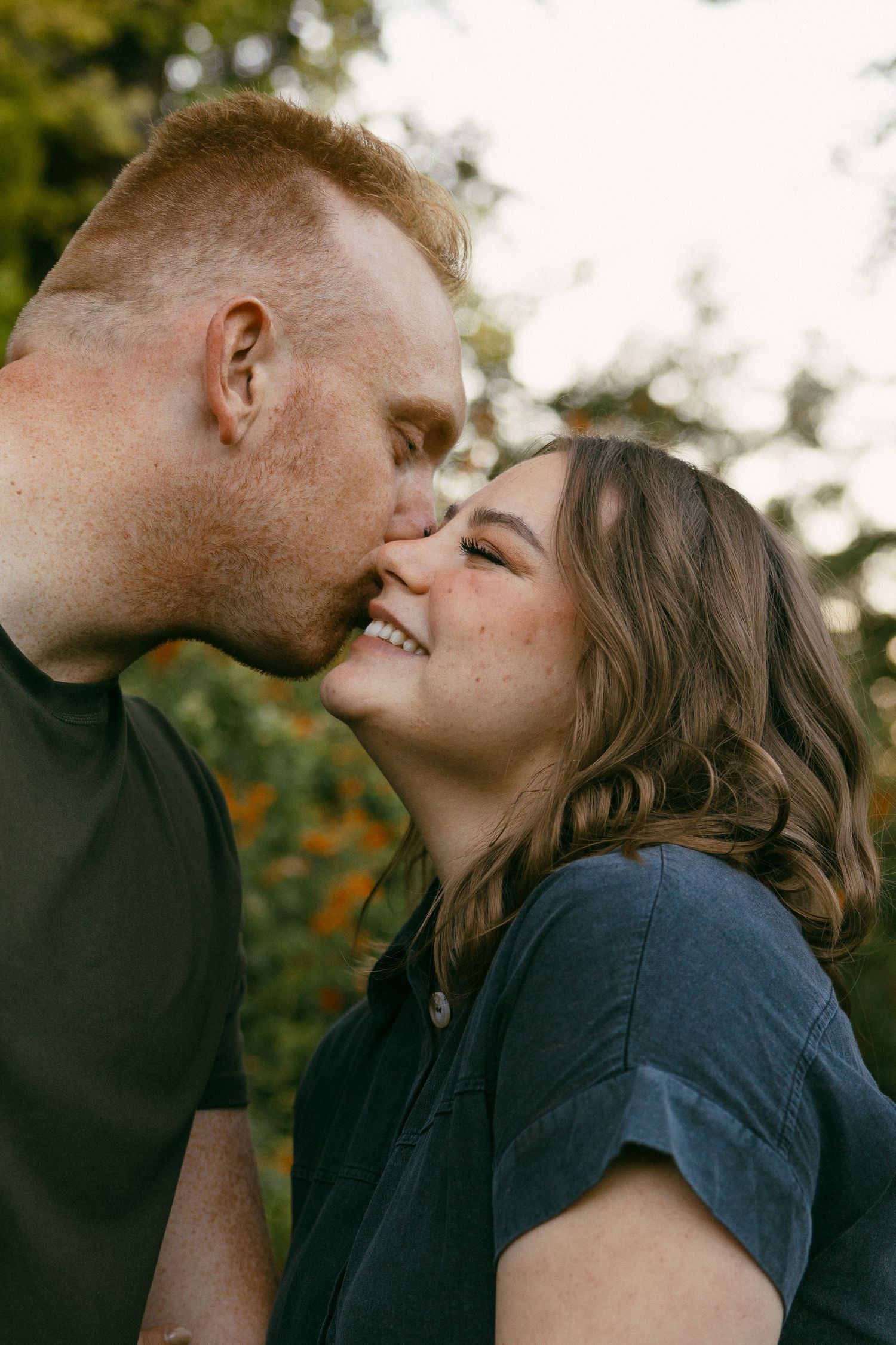 Intimate couple sharing a tender moment outdoors in natural lighting.