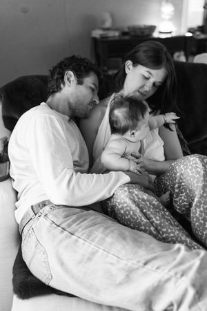 Black and white photo series captures intimate family moments as they cuddle together on a bed.