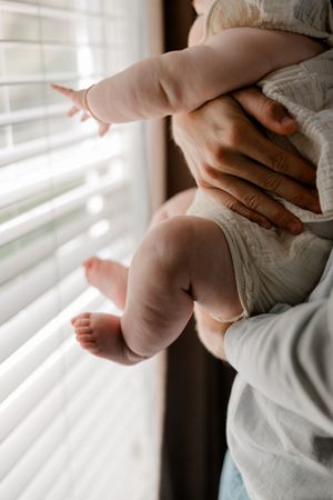 A close-up series of images showing gentle hands cradling a pregnant belly in soft window light.