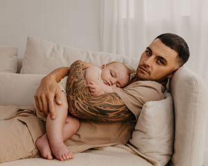 Peaceful moment of parent and sleeping toddler resting on beige couch.