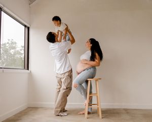 Two people practicing dance lifts and poses in a bright empty room with natural lighting.