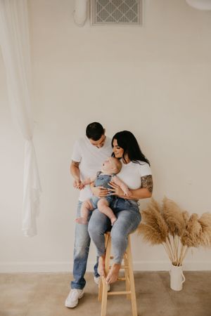 A couple shares tender moments indoors with pampas grass decorations and white walls.