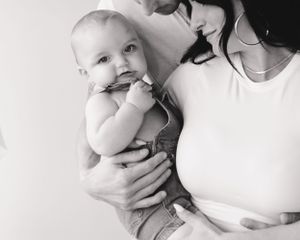 An artistic black and white close-up portrait of a parent with baby.