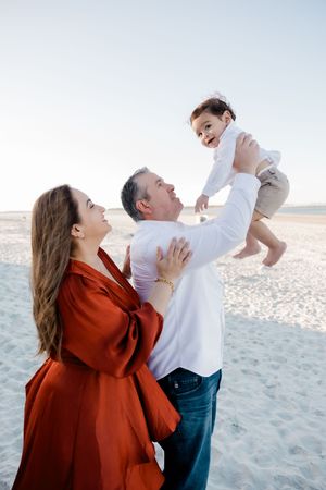 A family shares a joyful moment together on a sandy beach during a bright sunny day.