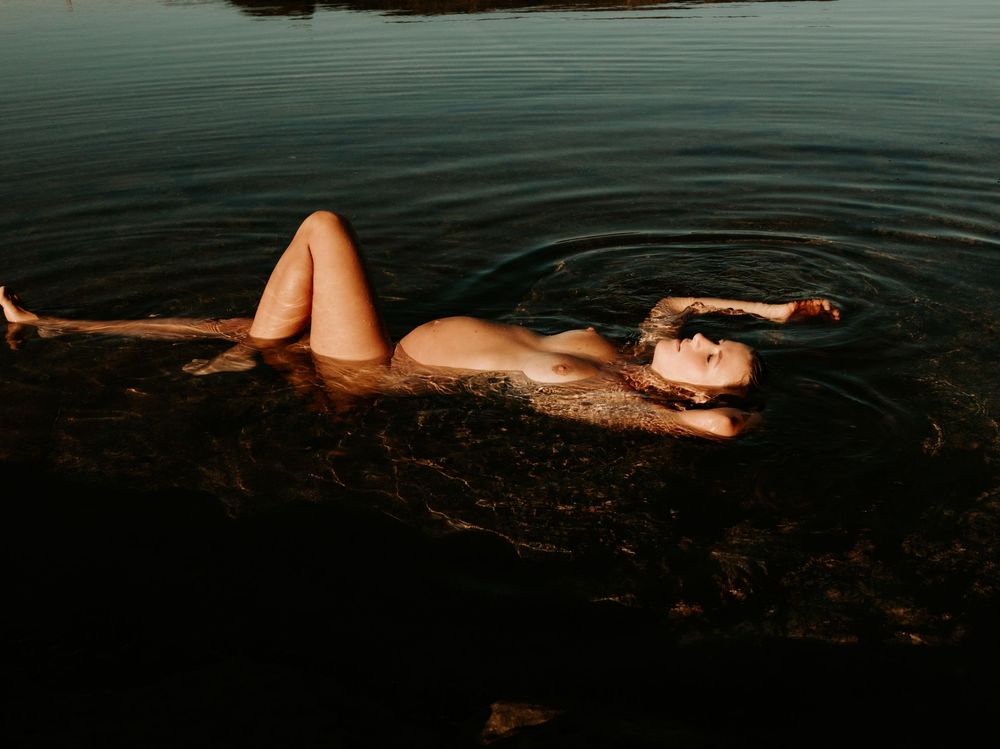 Artistic underwater photo sequence showing a pregnant mama to be floating gracefully in dark teal waters.