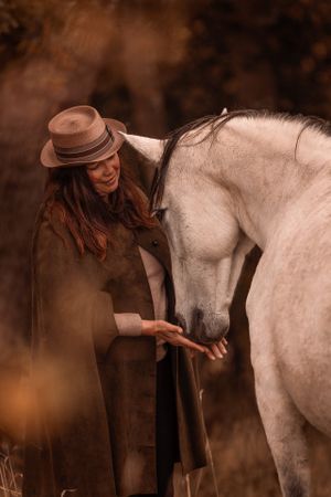 Frau kuschelt mit Schimmel Pferd
