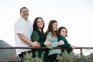 Happy family of four smiling together on an outdoor deck with scenic mountain views in the background.
